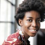 Close-up of a joyful Black woman with curly hair smiling indoors.